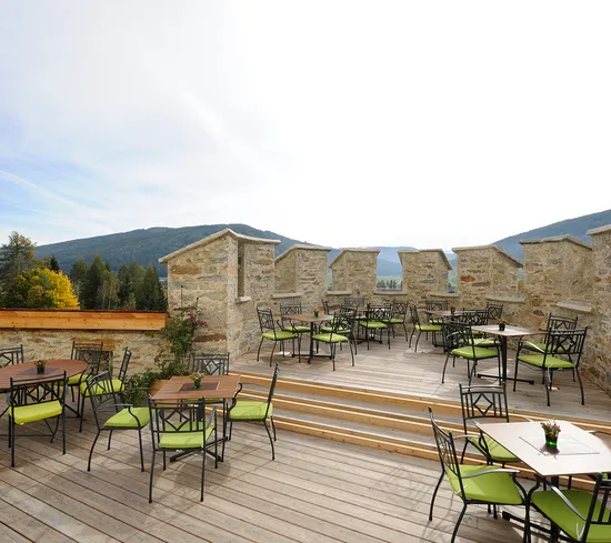 Terrazza esterna del ristorante con sedie verdi e vista sulle montagne