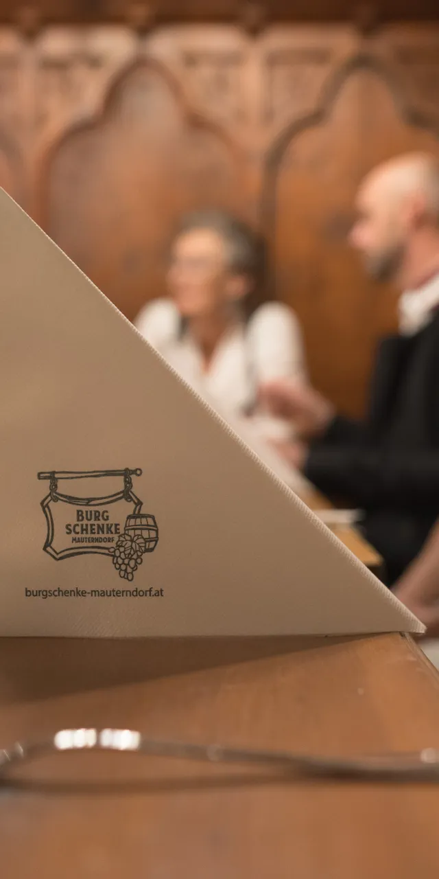Festlich gedeckter Tisch in der Burgschenke Mauterndorf mit unscharfen Gästen im Hintergrund