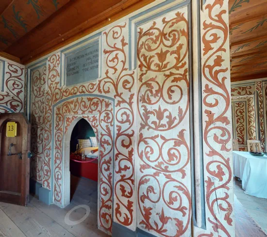 Interno storico decorato con motivi floreali, soffitto in legno e mobili in stile medievale