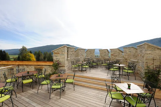 Terrazza esterna del ristorante con sedie verdi e vista sulle montagne