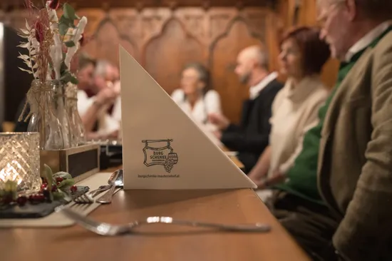 Festive dinner table at Burgschenke Mauterndorf with blurred guests in the background