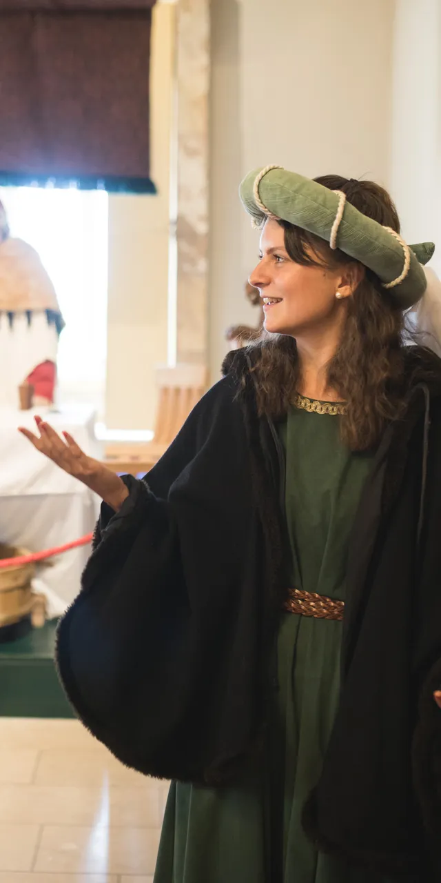 Tourist interacting with costumed guide in medieval museum exhibit with mannequins