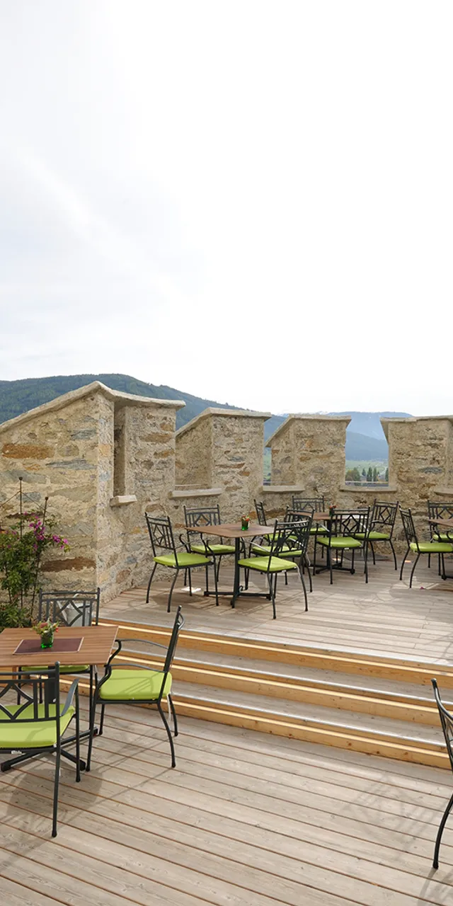 Terrazza esterna del ristorante con sedie verdi e vista sulle montagne