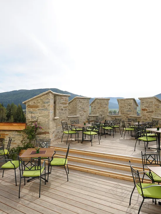 Restaurantterrasse im Freien mit grünen Stühlen und Bergblick